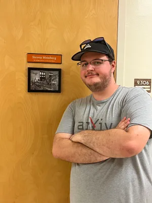 Dennis in front of a door that has Steven Weinberg's nameplate.